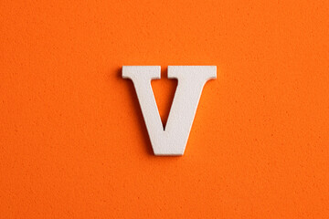 White wooden capital letter V on orange foamy background