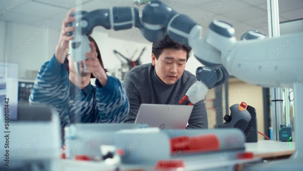 Poster Two Diverse Developers Brainstorming while Coding at Laptop. Asian Male Press Button at Control Panel. Colleagues Building, Configuring and Testing Robots. Technologies Concept. Slow Motion