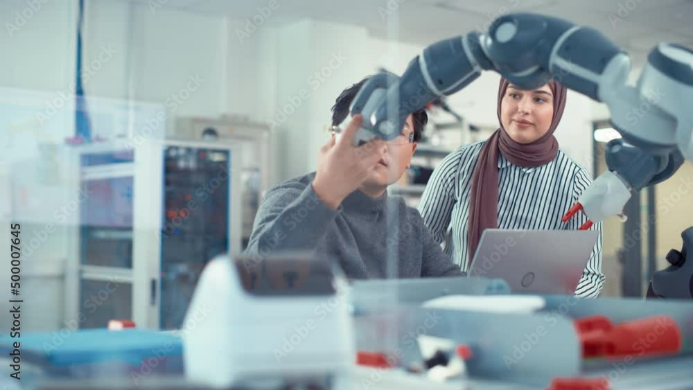 Poster Asian Engineer Repositioning and Examining Robotic Arm with Middle Eastern Female Colleague In Robotics Development Laboratory. Research into the Design, Operation and Performance of Robotic Mechanism