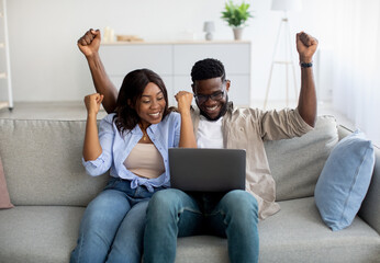 African american couple sitting on couch, using pc