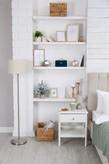 Fototapeta na wymiar Wall shelves with beautiful decor elements in stylish bedroom interior
