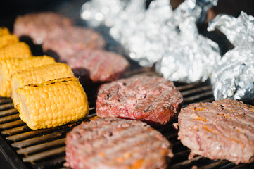 Maiskolben und Burger Patties auf einem Grillrost
