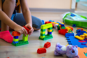 Fototapeta premium little girl playing with toys at home, Brickss type toys
