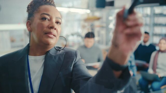 Black Female Teacher Write Big and Complex Mathematical Formula/ Equation on the Transparent Board while Hold Lecture with Diverse Students. Portrait View, Slow Motion