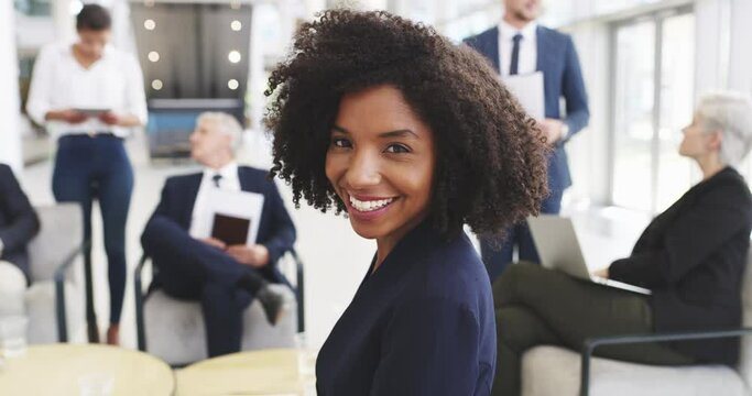 Every day is another opportunity to do better. Businesswoman smiling in an office with her colleagues in the background.confident young African woman with an afro at work. 