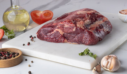 Raw meat. A large piece of beef chop on a marble cutting board with spices.