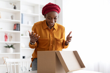 Amazed african american woman open delivery box at home