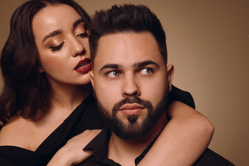 Handsome bearded man with sexy lady on light brown background