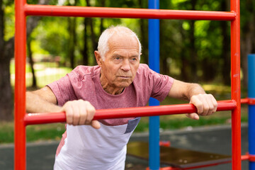 Obraz premium Old man in sportswear exercising push-ups outdoors
