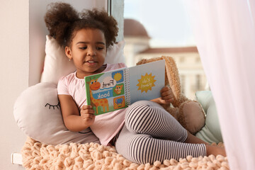 African American girl reading book at home