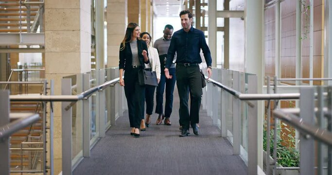 The only way to run a business, is together. Diverse group of  business people walking in the hallway of a modern office. Multiethnic employees taking a walk at a conference with career growth concept