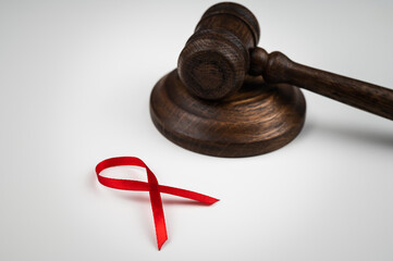 Judicial gavel and red ribbon on a white background. Symbol of the fight against AIDS.