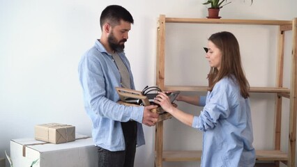 New house concept. Moving into a new apartment of a young friendly couple in love, putting things on the shelf, cozy, homely, floor box, indoor family lifestyle