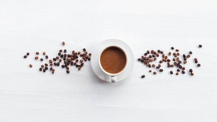 top view of coffee cup and coffee beans on white wooden background