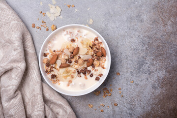Healthy breakfast of granola with fresh banana, nuts and yogurt