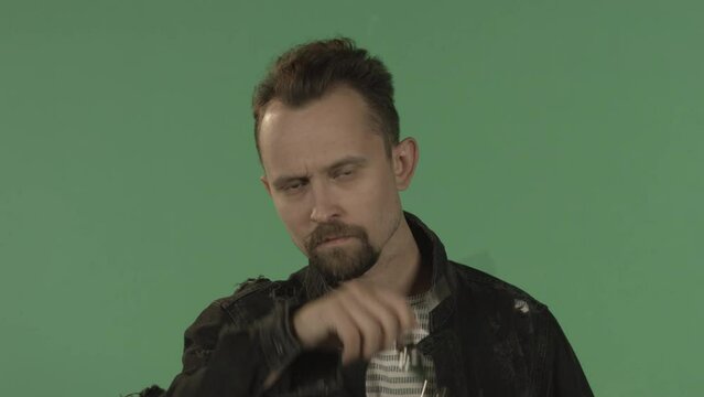 Portrait of a man on chroma key. The guy takes off his sunglasses. Heavy look.
