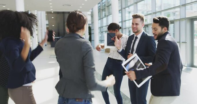 Grooving to one success after another. Excited happy diverse businesspeople dancing and having fun in a modern office. Overjoyed colleagues celebrating with a dance for a successful business project