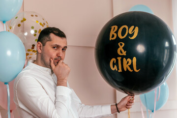 Expectant father is having a gender reveal party.Man holds a black balloon with the inscription Boy...