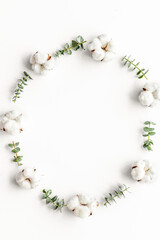 Flowers frame on white desk with fresh eucalyptus branches and cotton. Flat lay, top view, copy space