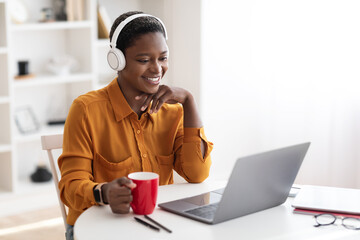 Young business woman having video conference with clients, drinking coffee