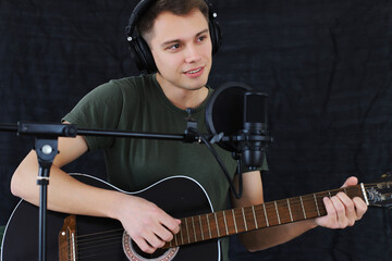The guy plays the guitar sings into the microphone