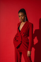 Fashion studio portrait of elegant Black woman wearing classic red double breasted suit, trendy...