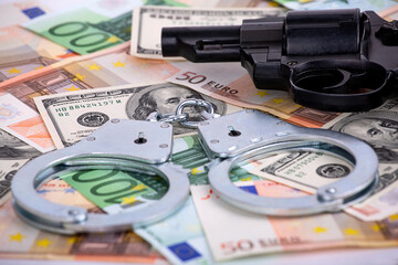 handcuffs and a gun lying on the money