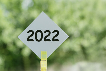 Close up of blue signpost with text of 2022 with green background