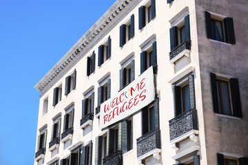 Banner with phrase WELCOME REFUGEES on building outdoors