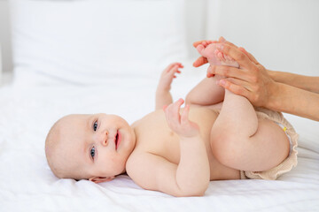 mom's hands hold the baby in diapers or does foot massage, love, mother's care for the baby, motherhood