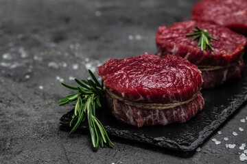 Beef medallions with rosemary and spices, Raw beef meat steak Tenderloin fillet on a dark background. banner, menu, recipe place for text, top view