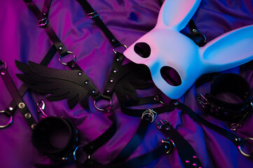rabbit mask and leather bdsm belts and accessories for bdsm games in neon light