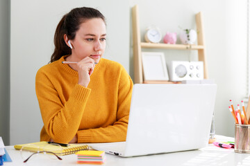 Portrait of young woman in headphones using laptop