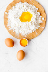Baking background with eggs and flour on white desk. Top view.