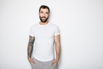 portrait of casual young man with beard and tattoo on white background