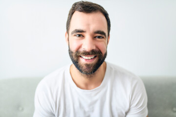 Fototapeta premium portrait of casual young man with beard on sofa at home
