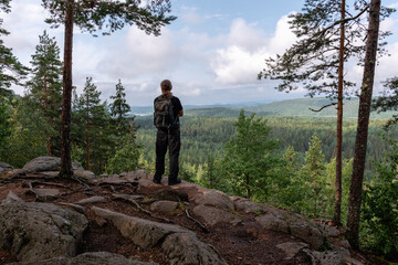 Man with backpack looking at scenic landscape from viewpoint in Finland