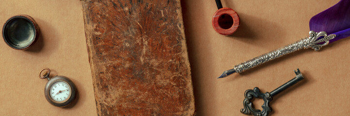 Mysterious vintage objects panorama. Old notebook, a retro key, a quill pen, and a Victorian pocket...