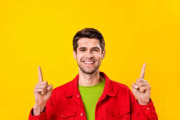 Portrait of attractive cheerful confident guy demonstrating up copy space ad idea isolated over bright yellow color background
