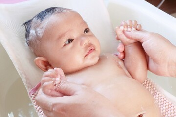 asian newborn baby bathing in bathtub.mother bathing her son in warm water.