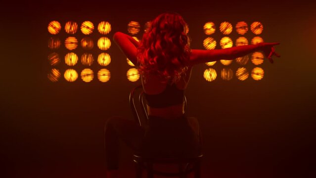 Woman dancing sitting backwards on chair nightclub. Blonde making erotic dance.