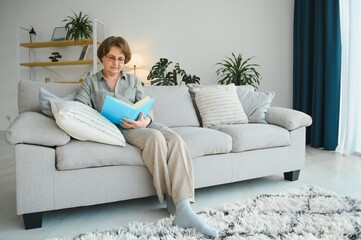 Portrait of relaxed senior woman sitting on sofa with book
