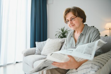 Older woman eelaxing and reading newspaper