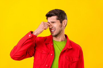 Portrait of attractive irritated guy touching closing noise bad smell isolated over bright yellow color background