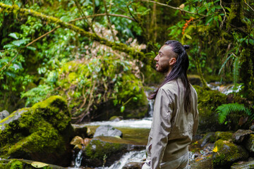 young long-haired latin man in the middle of the jungle admiring nature while hiking