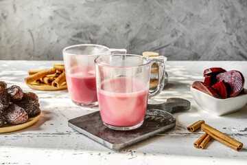 Healthy and tasty beetroot latte in two mugs with basic ingredients