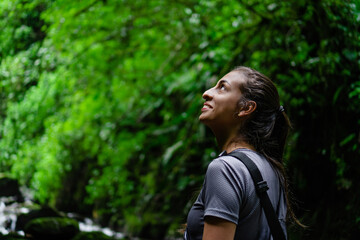 young latin woman in the jungle walking on a hike, admiring nature, looking up. low angle view....