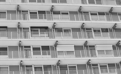 Low angle shot of a building with similar balconies and windows in greyscale