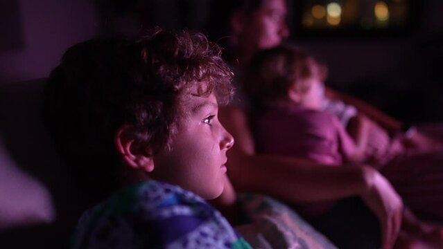 Child watching television screen at night