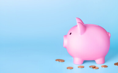 Pink piggy bank and coins money on blue background. Finance saving concept.